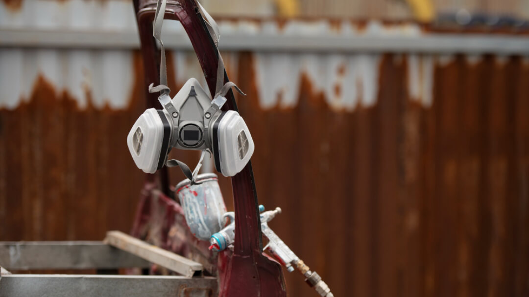 Un masque respiratoire à double filtre accroché dans un atelier de carrosserie.