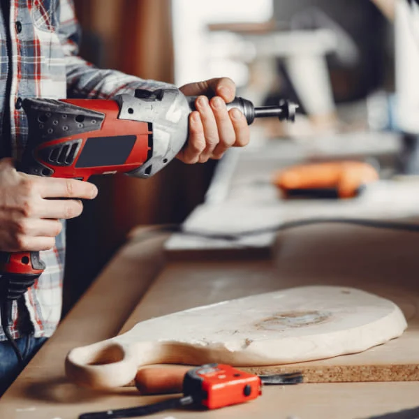 Une personne utilise une perceuse pour créer une planche à découper en bois.