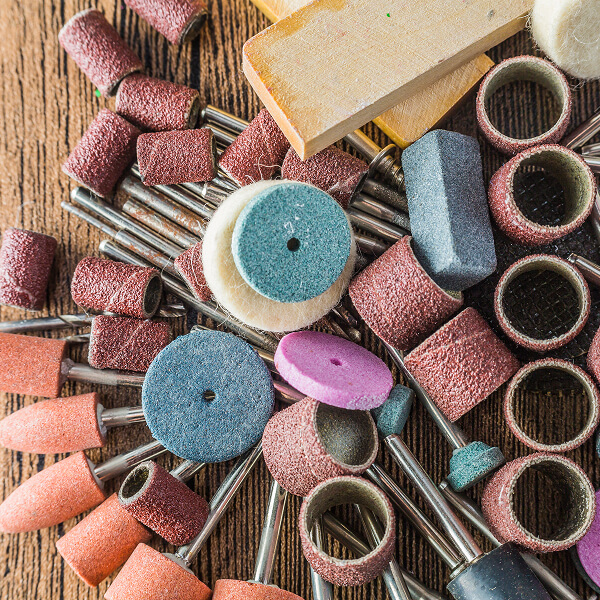 Une pile d'outils de ponçage variés, incluant des blocs, des papiers et des tampons abrasifs.