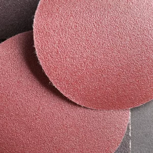 Trois disques de ponçage rouges en gros plan, montrant leur texture et leur forme circulaire.